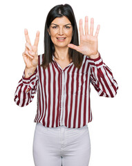 Beautiful brunette woman wearing striped shirt showing and pointing up with fingers number seven while smiling confident and happy.