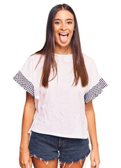 Young hispanic woman wearing casual clothes sticking tongue out happy with funny expression....