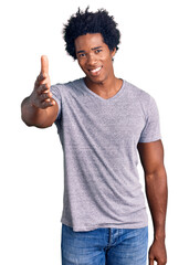 Handsome african american man with afro hair wearing casual clothes smiling friendly offering handshake as greeting and welcoming. successful business.