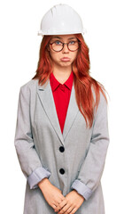Young redhead woman wearing architect hardhat depressed and worry for distress, crying angry and afraid. sad expression.