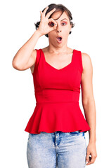 Beautiful young woman with short hair wearing casual style with sleeveless shirt doing ok gesture shocked with surprised face, eye looking through fingers. unbelieving expression.