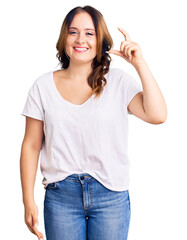 Young beautiful caucasian woman wearing casual white tshirt smiling and confident gesturing with hand doing small size sign with fingers looking and the camera. measure concept.