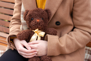 The girl is holding a cute teddy bear in her hands.