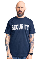 Young handsome man wearing security t shirt in shock face, looking skeptical and sarcastic, surprised with open mouth