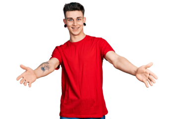 Young caucasian boy with ears dilation wearing casual red t shirt looking at the camera smiling with open arms for hug. cheerful expression embracing happiness.