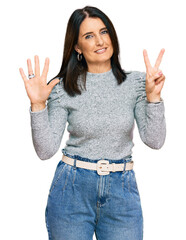 Middle age brunette woman wearing casual clothes showing and pointing up with fingers number seven while smiling confident and happy.