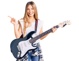 Beautiful caucasian woman with blonde hair playing electric guitar smiling happy pointing with hand and finger to the side