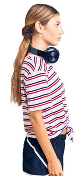 Beautiful caucasian woman with blonde hair wearing gym clothes and using headphones looking to side, relax profile pose with natural face with confident smile.