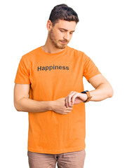 Handsome young man with bear wearing tshirt with happiness word message checking the time on wrist watch, relaxed and confident