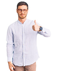 Handsome young man with bear wearing elegant business shirt and glasses doing happy thumbs up...