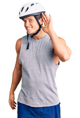 Young handsome man wearing bike helmet smiling with hand over ear listening an hearing to rumor or gossip. deafness concept.