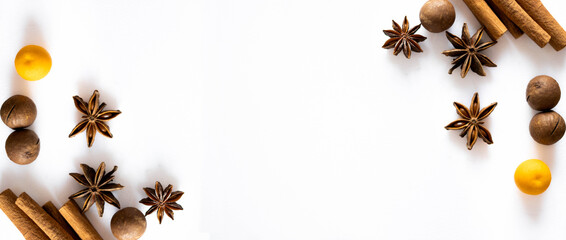 Banner with Christmas spices. Cinnamon, star anise, nuts, mandarin, and kumquat are isolated on a white background. Top view. The atmosphere of Christmas and New Year