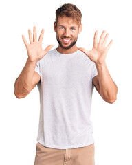 Fototapeta premium Young caucasian man wearing casual white tshirt showing and pointing up with fingers number ten while smiling confident and happy.
