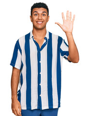 Young arab man wearing casual clothes showing and pointing up with fingers number five while smiling confident and happy.