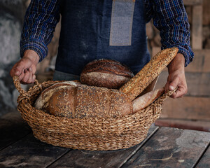 Cesta con variedad de pan sostenida por manos. - obrazy, fototapety, plakaty