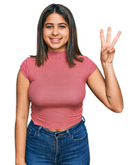 Young hispanic girl wearing casual t shirt showing and pointing up with fingers number three while smiling confident and happy.