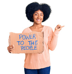 Young african american girl holding power to the people banner smiling happy pointing with hand and finger to the side