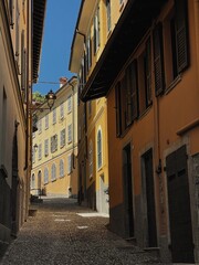 Old historic architecture in Italy. Traditional European old town building. Wooden windows, shutters and colourful pastel walls with sunlight shadows. Aesthetic summer vacation travel background