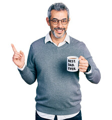 Middle age hispanic man with grey hair drinking mug of coffee with best dad ever message smiling...