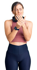 Beautiful caucasian young woman wearing gym clothes and using headphones suffering pain on hands...