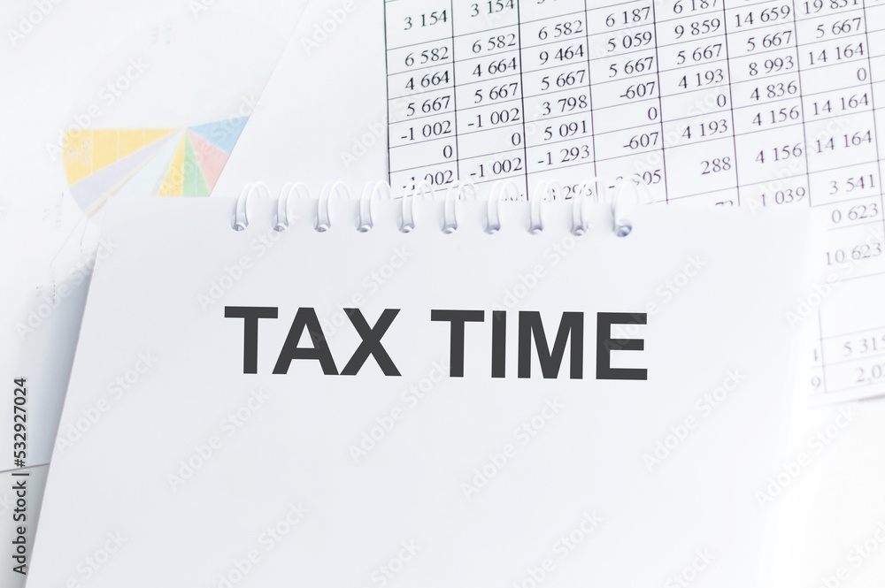 Poster tax time text on notepad on the background of reports and charts