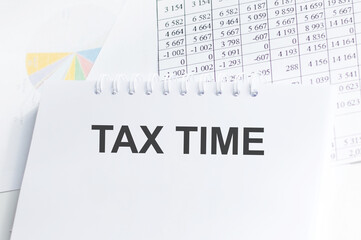 Tax time text on notepad on the background of reports and charts