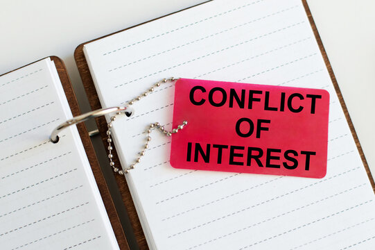 CONFLICT OF INTEREST text on a card against the background of an open notebook on the table