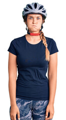 Beautiful caucasian woman wearing bike helmet puffing cheeks with funny face. mouth inflated with air, crazy expression.