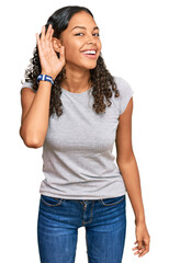 Young african american girl wearing casual clothes smiling with hand over ear listening an hearing...