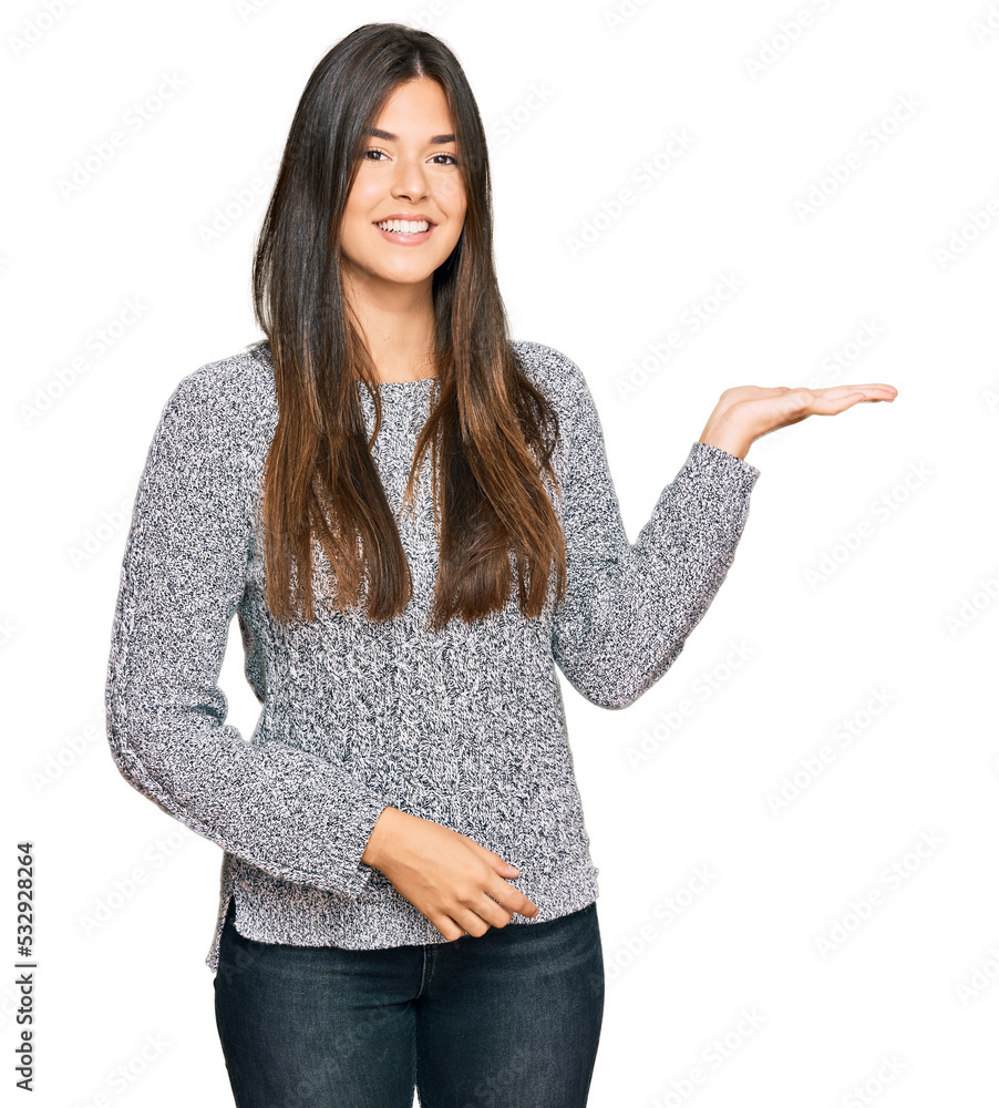 Wall mural young brunette woman wearing casual winter sweater smiling cheerful presenting and pointing with pal