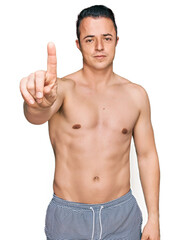 Fototapeta premium Handsome young man wearing swimwear shirtless pointing with finger up and angry expression, showing no gesture