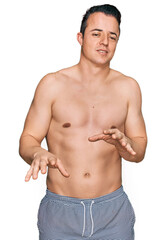 Fototapeta premium Handsome young man wearing swimwear shirtless disgusted expression, displeased and fearful doing disgust face because aversion reaction.