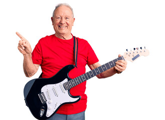 Senior handsome grey-haired man playing electric guitar smiling happy pointing with hand and finger to the side