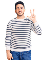 Young hispanic man wearing casual clothes showing and pointing up with fingers number three while smiling confident and happy.