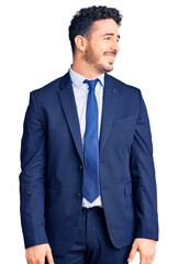Young hispanic man wearing business clothes looking away to side with smile on face, natural expression. laughing confident.