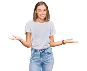 Beautiful young blonde woman wearing casual white t shirt smiling cheerful with open arms as friendly welcome, positive and confident greetings