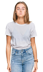 Obraz premium Beautiful young blonde woman wearing casual white t shirt puffing cheeks with funny face. mouth inflated with air, crazy expression.