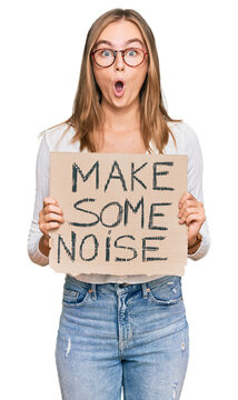 Beautiful blonde woman holding make some noise banner scared and amazed with open mouth for surprise, disbelief face