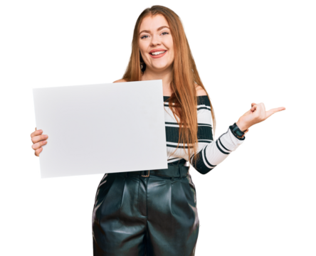 Young beautiful redhead woman holding blank empty banner smiling happy pointing with hand and finger to the side
