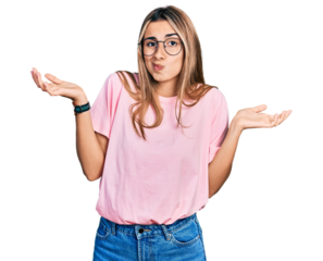 Hispanic young woman wearing casual t shirt and glasses clueless and confused expression with arms and hands raised. doubt concept.