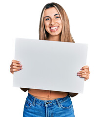 Hispanic young woman holding blank empty banner smiling with a happy and cool smile on face. showing teeth.