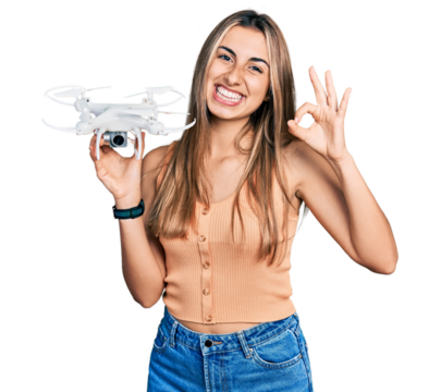 Hispanic young woman holding drone doing ok sign with fingers, smiling friendly gesturing excellent symbol