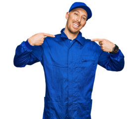 Bald man with beard wearing builder jumpsuit uniform looking confident with smile on face, pointing oneself with fingers proud and happy.