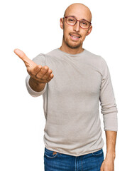 Bald man with beard wearing casual clothes and glasses smiling friendly offering handshake as greeting and welcoming. successful business.