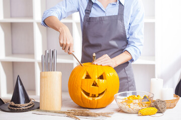 woman at wooden table carving pumpkin for halloween