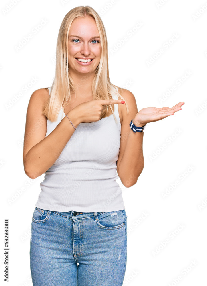 Canvas Prints Young blonde girl wearing casual style with sleeveless shirt amazed and smiling to the camera while presenting with hand and pointing with finger.