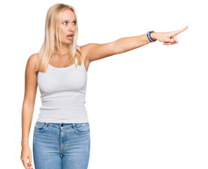 Young blonde girl wearing casual style with sleeveless shirt pointing with finger surprised ahead, open mouth amazed expression, something on the front