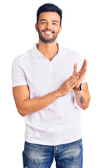 Young handsome hispanic man wearing casual clothes clapping and applauding happy and joyful,...