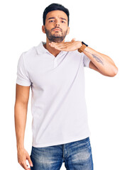 Fototapeta premium Young handsome hispanic man wearing casual clothes cutting throat with hand as knife, threaten aggression with furious violence