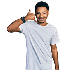 Young african american man wearing casual white t shirt smiling doing phone gesture with hand and fingers like talking on the telephone. communicating concepts.